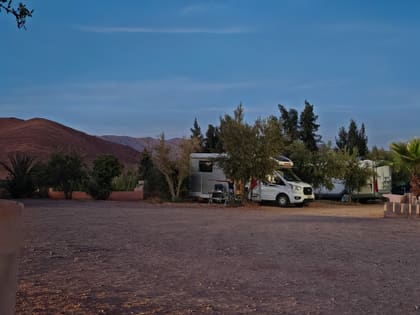Campervans at a site near Taznakhte, mountains behind them in the evening light